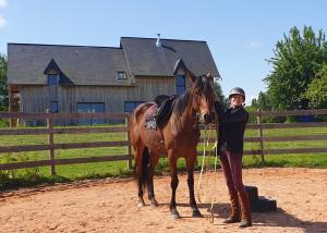a woman standing next to a brown horse at Le Refuge en bois nuit insolite en pleine Nature in Glanville +10 photos