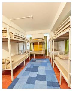 a room with four bunk beds and a blue rug at Zion Backpackers Hostel Shillong in Shillong +5 photos