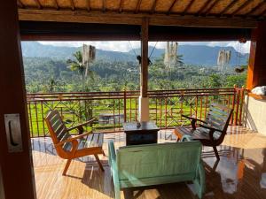 a balcony with two chairs and a table with a view at Makna Homestay and Spa in Sidemen