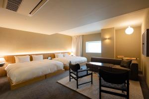 a hotel room with two beds and a couch at Hotel Lepo Chahal in Matsuyama