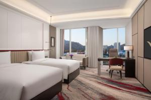 a hotel room with two beds and a desk at Movenpick by Accor Qingdao Sunmei in Qingdao +52 photos