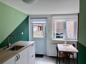 a kitchen with a sink and a table and two windows at The Sleep Studio in Sint Annaland