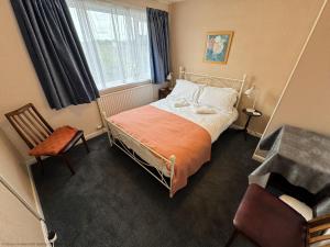 a bedroom with a bed and a chair and a window at Foxbrae Cottage in Rockcliffe