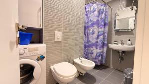a bathroom with a toilet sink and a washing machine at Vala Mar Apartments by Four C in Hamallë +105 photos