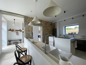a kitchen with a sink and a counter with chairs at Maison haut de gamme 14 couchages - Baie du Mont Saint Michel in Champeaux