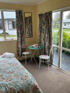 a bedroom with a bed and a table and windows at Green Hayes Estate Rentals - Green Hayes Cabin in Temuka