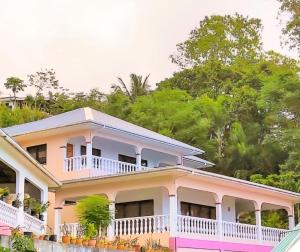 una casa rosa con un balcone avvolgente di Vilea Frangipani Ground Floor 2 bedroom Apartment a Mahe