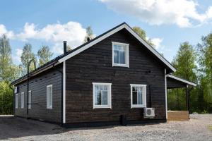 een klein zwart huis met witte ramen bij Villa Ruuska 