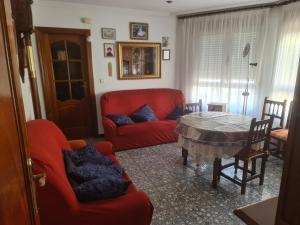 a living room with a red couch and a table at Casa acogedora in Sahagún
