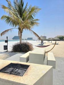 ラス・アル・ハイマにあるSeaview Escape Family Two-Room Apartment with Seaviewのベンチのあるビーチの隣に立つヤシの木