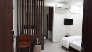a bedroom with a bed and a chair and a tv at Anantha Shaiya in Tiruchchirāppalli