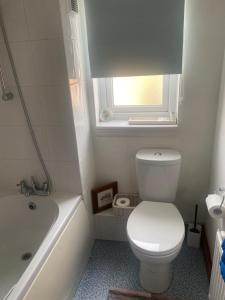 a bathroom with a toilet and a tub and a window at Riverside cottage in Deeping Saint James +17 photos