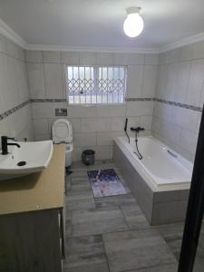 a bathroom with a sink and a tub and a toilet at Emakhonkosi Guest House in Ballito +26 photos