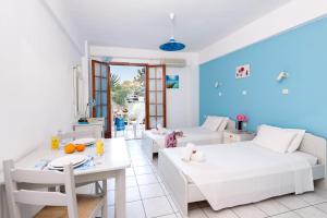 een woonkamer met 2 bedden en een tafel bij Kostas Apartments in Stalida