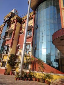 un grand bâtiment avec des plantes devant lui dans l'établissement Hotel Laxmi Palace, à Dehradun