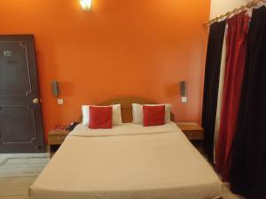 une chambre avec un lit avec deux oreillers rouges dans l'établissement Hotel Laxmi Palace, à Dehradun