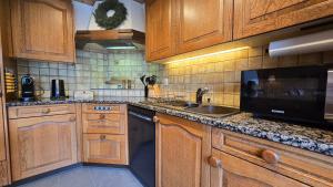 a kitchen with wooden cabinets and a sink and a microwave at Alpine Loft, Central, Balcony, Parking, Family,PS5 in Frutigen