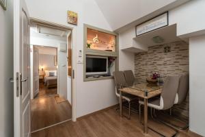 Un comedor con mesa y sillas y un televisor. en Apartman Neve, en Dubrovnik