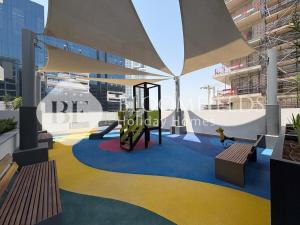 Bloomfields Deluxe Studio In Azizi Riviera في دبي: ملعب به زلاجة ومقاعد في مبنى