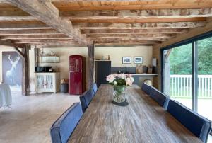 a room with a wooden table with blue chairs and a vase of flowers at Maison Priats in Lasseube