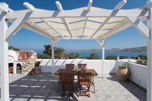 a wooden table and chairs under a white pergola at PAROS APARTMENT MELAS b4 in Parikia