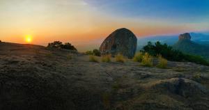 a sunset on a mountain with a large rock at Royal Breeze Resort Sigiriya in Sigiriya
