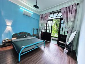 a blue bedroom with a bed and a window at Gem's House 1- Balcony with Riverside View in Ho Chi Minh City