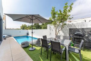un patio con tavolo, ombrellone e piscina di Mira Luz - Luz de Tavira a Luz de Tavira