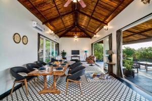 un salon avec une table et des chaises en bois dans l'établissement SaffronStays Blissfort, à Malavli