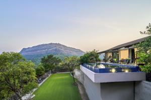 une vue d'une maison avec une pelouse et une montagne dans l'établissement SaffronStays Blissfort, à Malavli