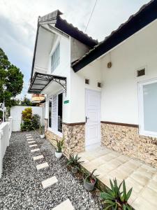 a white house with a door and some plants at Puri 11 Homestay Jogja in Ngemplak