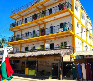 a yellow building with balconies and a store at VaoVao Hotel in Nosy Be