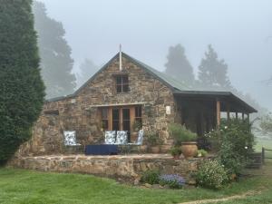 ein Steinhaus mit einer Veranda auf einem Feld in der Unterkunft Strathwold Cottages in Machadodorp