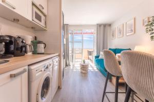 cocina con lavadora y mesa con sillas en Appartement Cap Esterel - piscine, en Saint-Raphaël