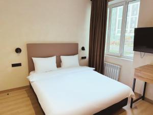 a bedroom with a white bed and a window at Tan Hotel Astana in Astana