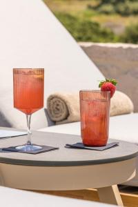two glasses of juice and a strawberry on a table at Golden Milos Beach Ηouse by Domotel in Provatas