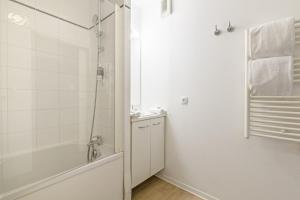 a white bathroom with a shower and a sink at Lagrange Apart'Hotel l’Escale Marine in La Rochelle +22 photos
