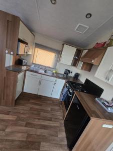 a small kitchen with white cabinets and black appliances at Chasing The Dream k52, Ingoldmells, FREE WIFI in Ingoldmells