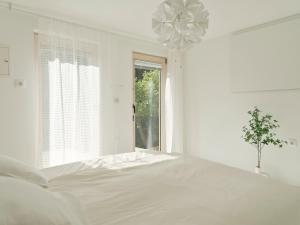 a white bedroom with a large bed and a window at Peak & Pause in Bistrica pri Limbušu