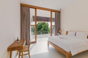 een slaapkamer met een bed, een bureau en een groot raam bij Arjuna Villa by Betterplace in Dalung +39 foto's