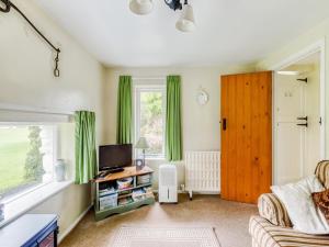 a living room with a couch and a tv and a window at Secluded Holiday Home in Ceredigion with Garden in Pennant