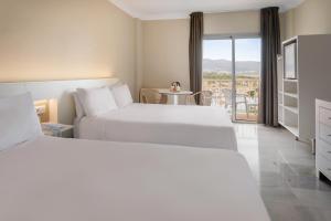 a hotel room with two beds and a table at Sol Guadalmar in Málaga