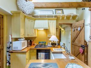 a kitchen with wooden cabinets and a sink and a microwave at Little Tarbet in Dornoch