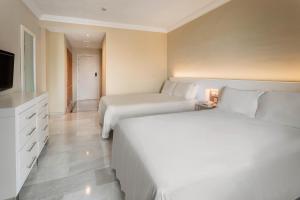 a hotel room with two beds and a television at Sol Guadalmar in Málaga
