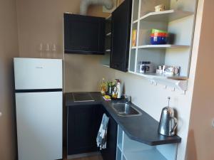 a kitchen with black cabinets and a white refrigerator at Kesklinna korter in Kuressaare