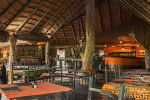 a dining room with tables and chairs and trees at Thamalakane River Lodge in Maun
