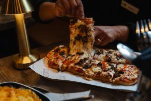 a person eating a slice of pizza on a table at CoDE Pod – The CoURT - Edinburgh in Edinburgh