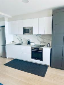 a white kitchen with a stove and a microwave at Alojamientos Ría de Vigo & Alborada in Moaña