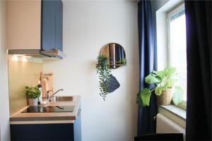 a kitchen with a sink and a window with plants at Allihoop Ängby Aces in Stockholm
