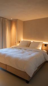 a bedroom with a large bed with white sheets at Meme Wiesje in Oudenburg